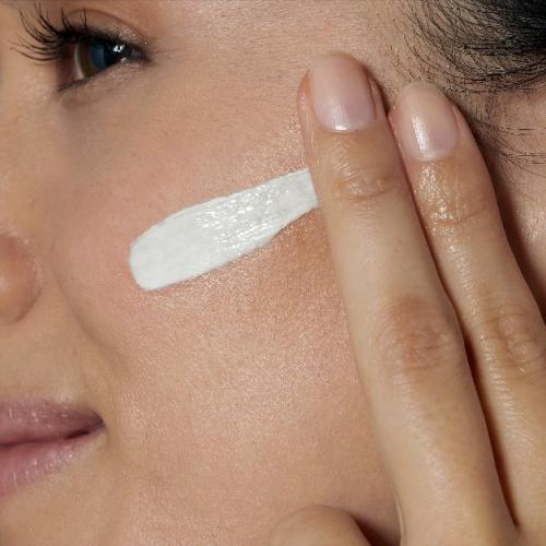 Woman with a radiant glow on her face, holding CeraVe Advanced Repair Ointment
